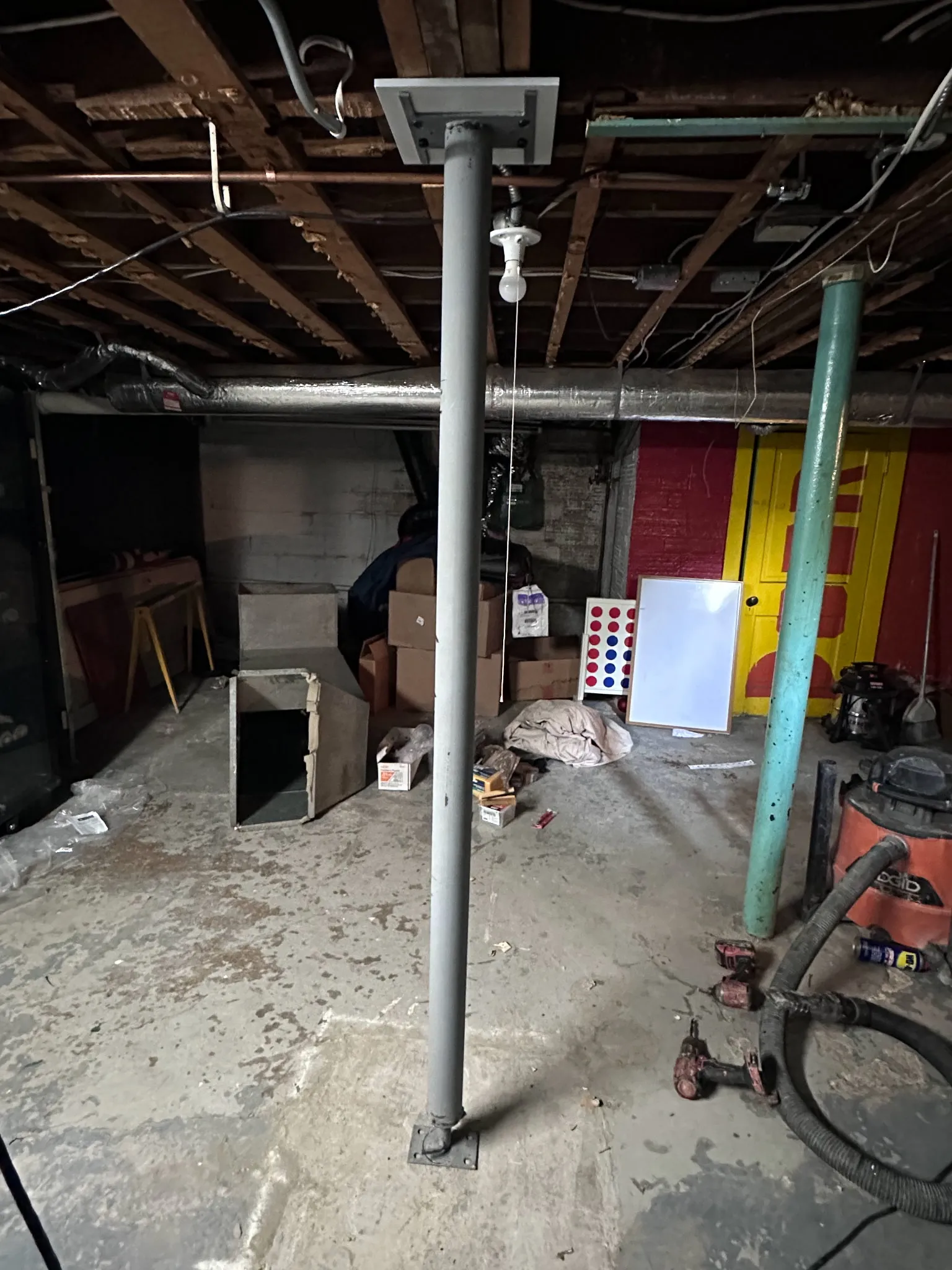 Adjustable steel support column installed in basement to support beam and joists