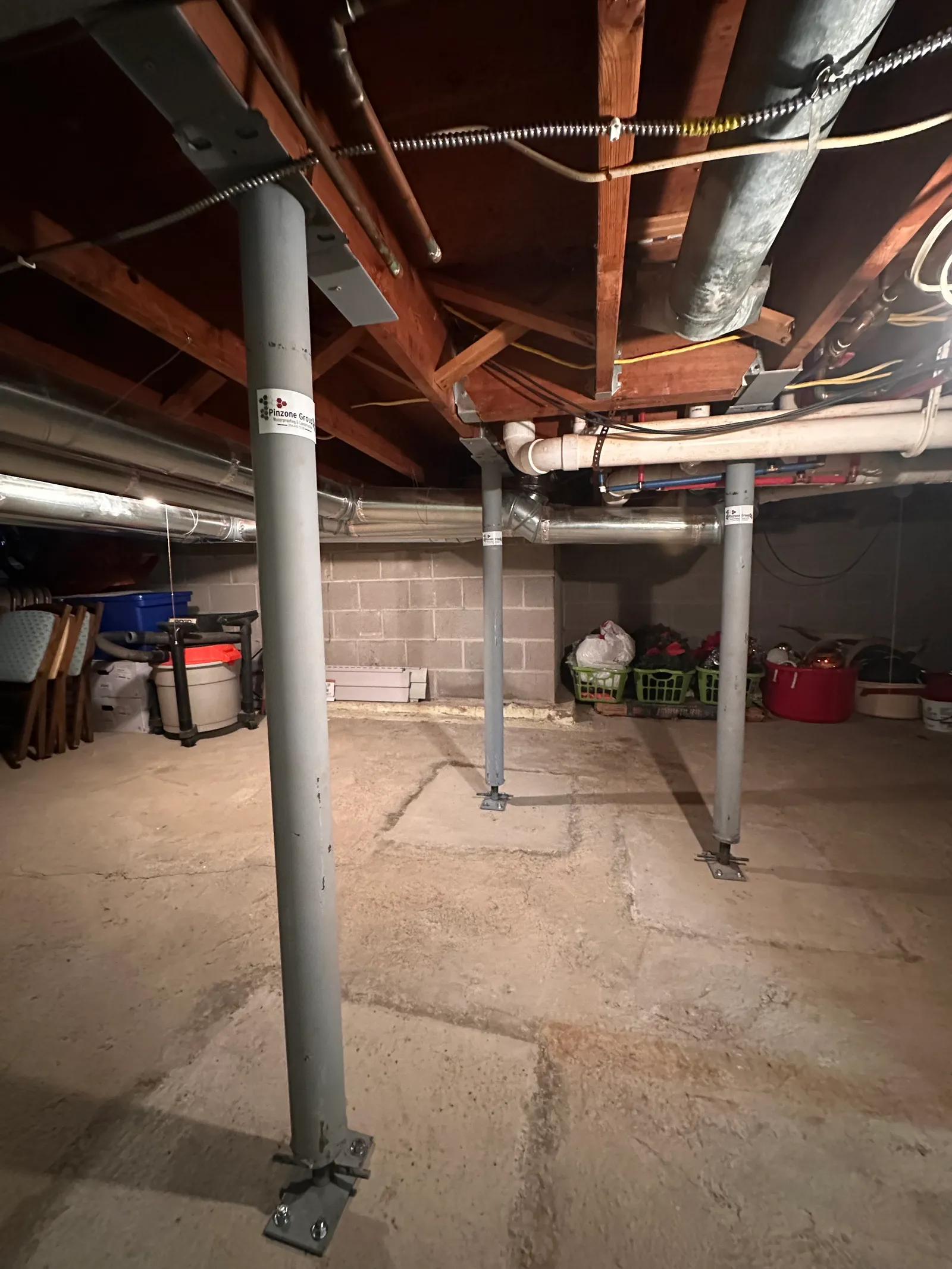 Row of four steel support columns in basement supporting floor beam